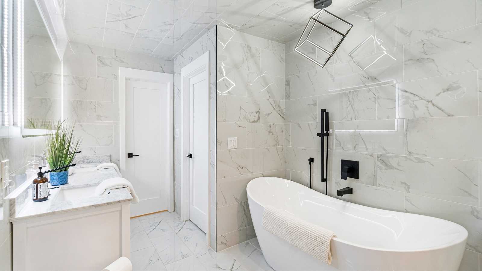 luxurious-modern-bathroom Modern bathroom featuring a freestanding tub, marble tile walls, and a stylish vanity with greenery and sleek fixtures.